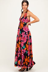 woman wearing a black floral maxi dress with a halter neck and vibrant pink and orange flowers