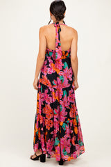 woman wearing a black halter neck maxi dress with colorful floral patterns and an open back
