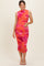 woman wearing an orange floral maternity dress with ruching detailing and a fitted silhouette, showing her baby bump