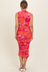 woman wearing a bright orange floral maternity dress with ruching and a fitted silhouette, showing her baby bump from the back
