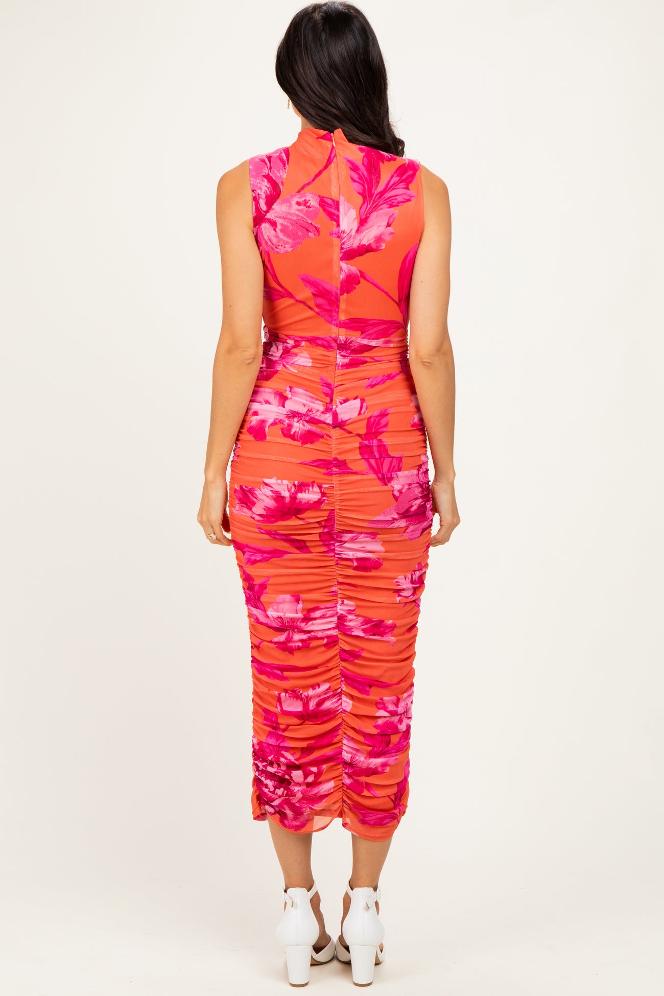 woman wearing a vibrant pink floral midi dress with ruched detailing and a high neckline from the back