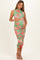 woman wearing a floral green maternity dress with ruched details, holding her baby bump