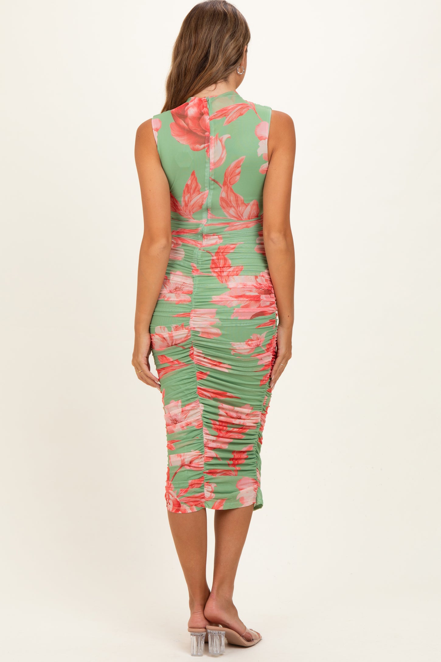 woman wearing a green floral maternity dress with a ruched back and sleeveless design