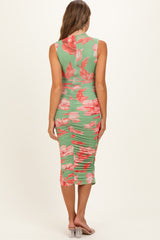 woman wearing a green floral maternity dress with a ruched back and sleeveless design