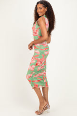 woman wearing a green floral midi dress with side ruching and a fitted silhouette