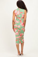 woman wearing a green floral bodycon dress with ruching detailing and a mid-length hemline, seen from the back