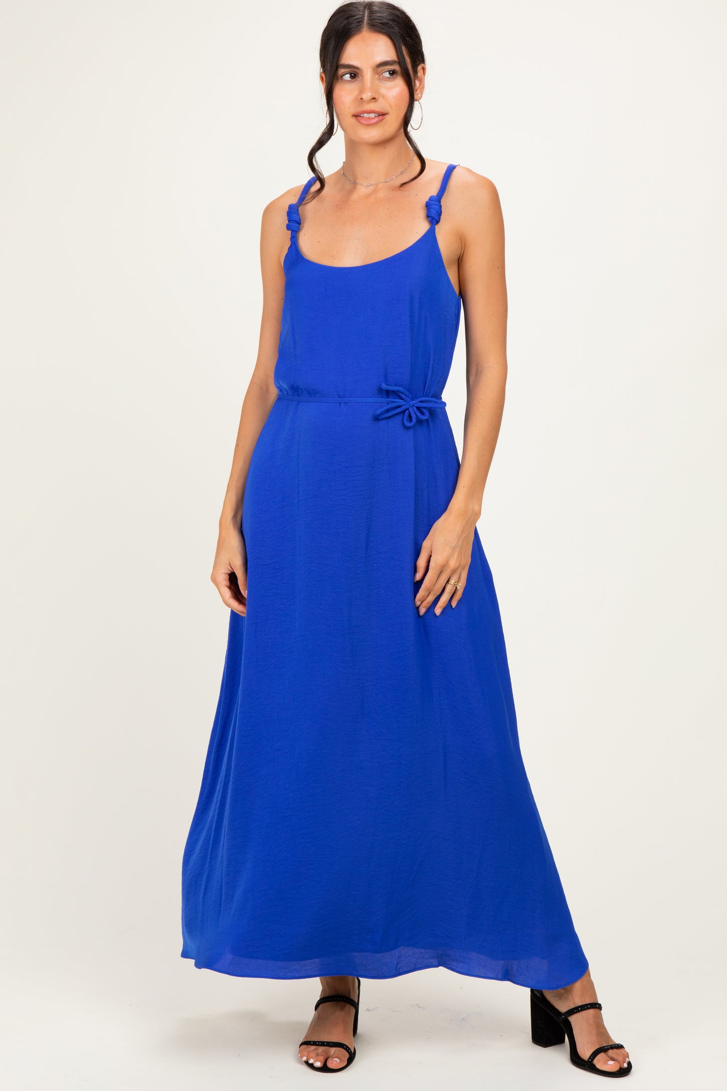 woman wearing a bright blue maxi dress with adjustable straps and a tie waist detail