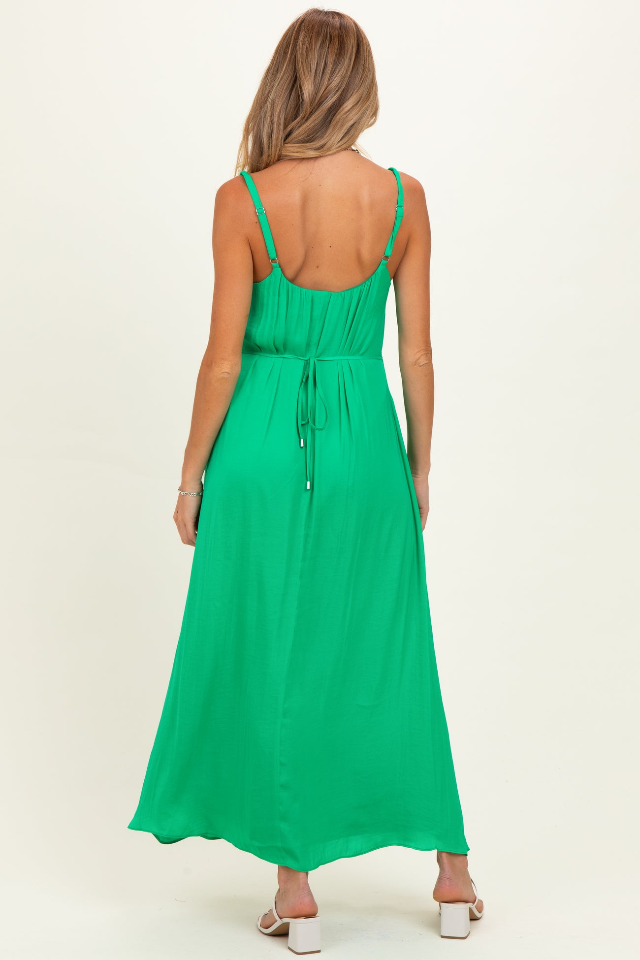 woman wearing a green maxi maternity dress with adjustable spaghetti straps and tie waist detail