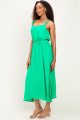 woman wearing a bright green spaghetti strap midi dress with a cinched waist and flowy silhouette