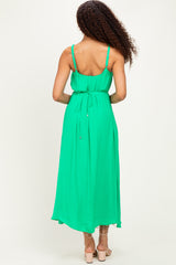 woman wearing a back view of a bright green spaghetti strap maxi dress with a tie at the waist