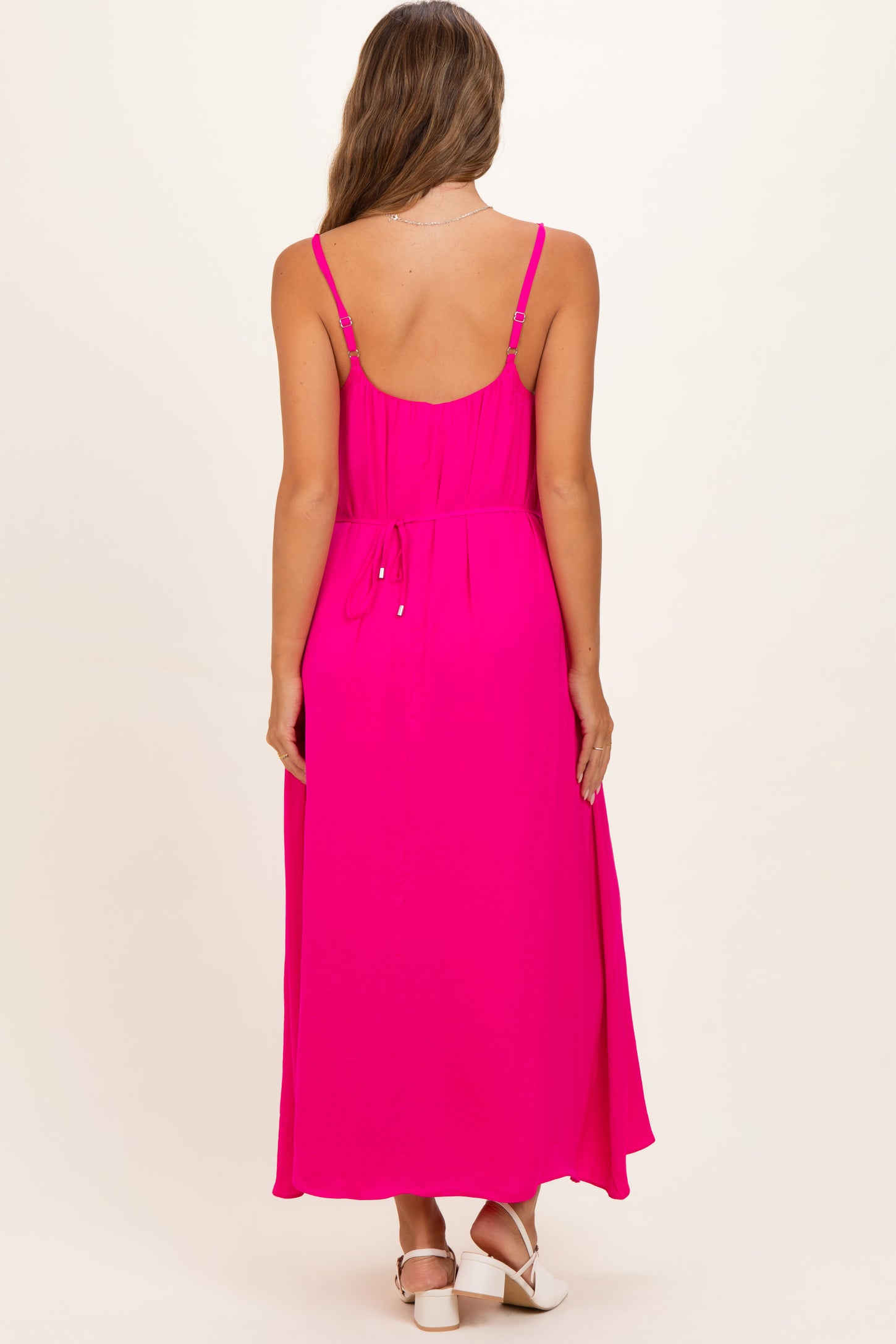 woman wearing a bright pink maternity maxi dress with adjustable spaghetti straps and a drawstring at the waist
