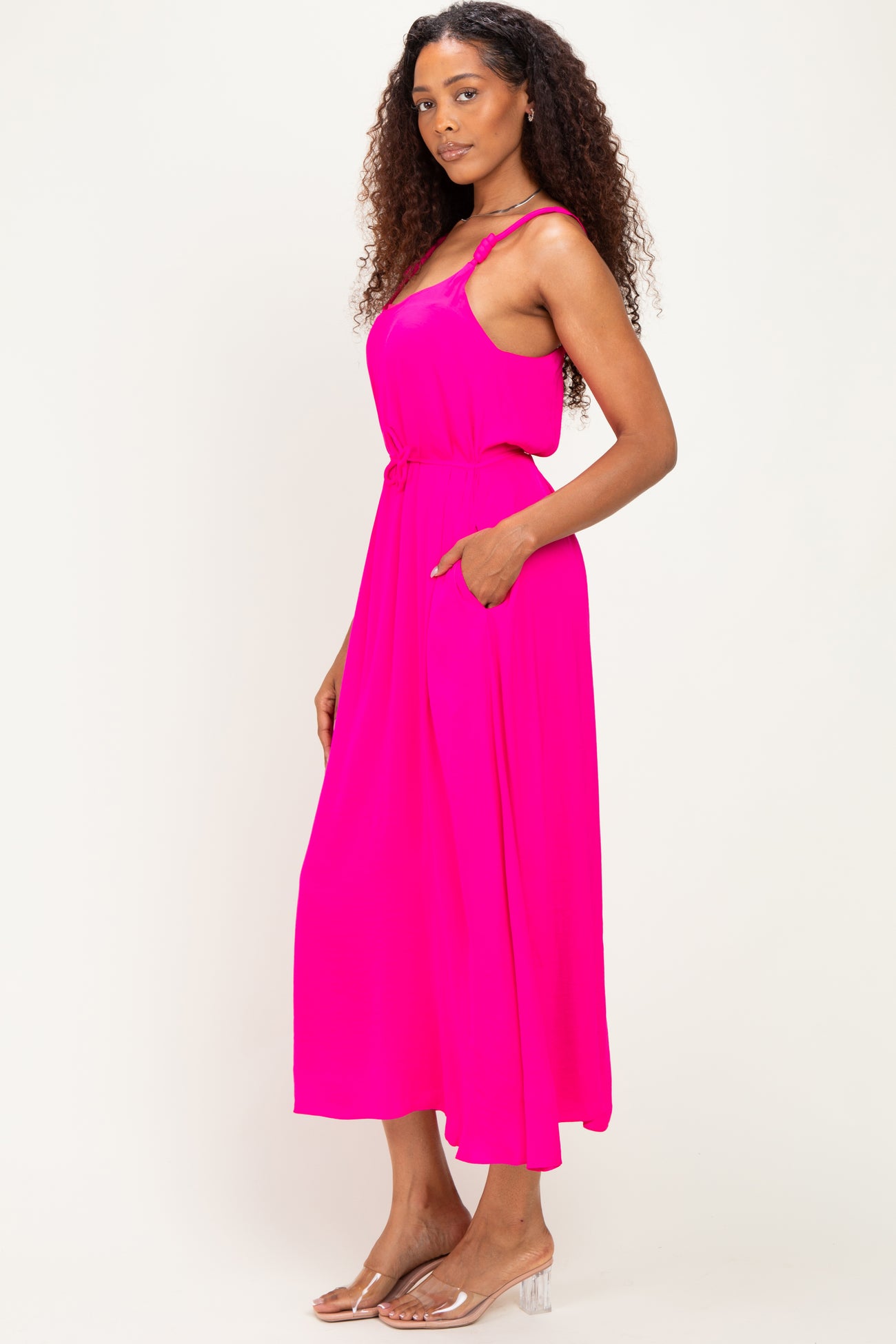 woman wearing a bright pink sleeveless maxi dress with a relaxed fit and side pockets