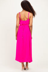 woman wearing a bright pink maxi dress with a tied waist and adjustable straps, viewed from the back