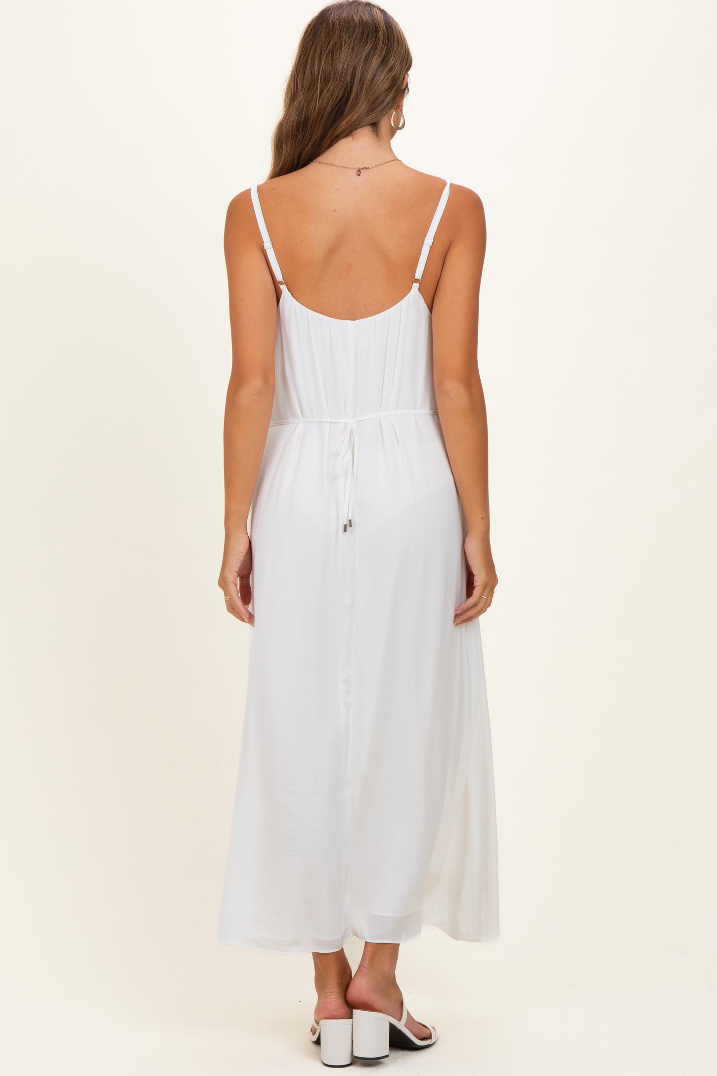 woman wearing a white maternity maxi dress with a tie detail at the back and adjustable straps