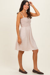 woman wearing a light pink spaghetti strap dress with smocked bodice and flared skirt, paired with brown flats
