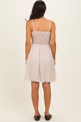 woman wearing a light pink smocked back sundress with thin straps, viewed from the back