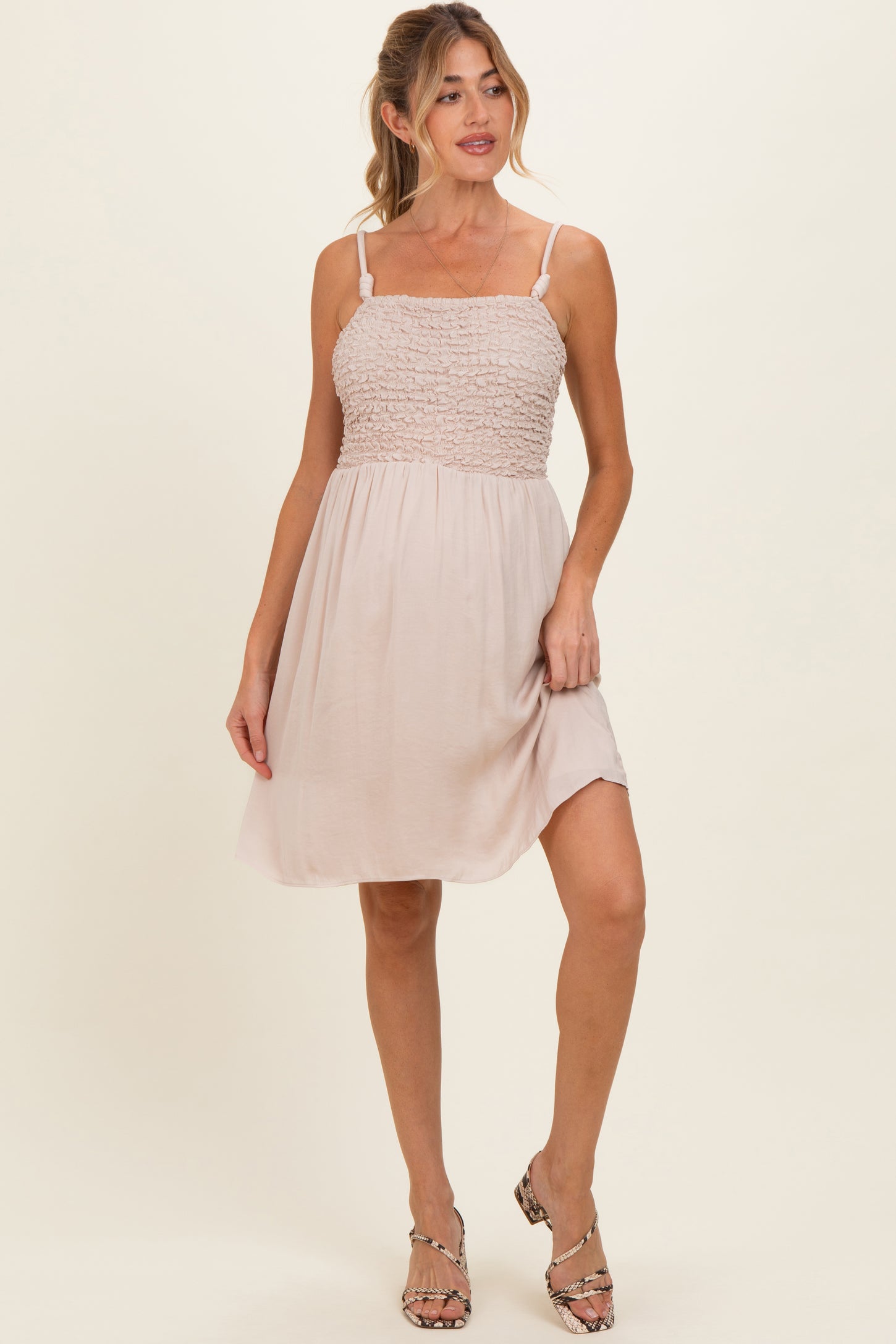woman wearing a light beige maternity dress with smocked bodice and adjustable straps