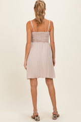 woman wearing a light beige maternity dress with a smocked bodice and a flowy skirt, showing the back view