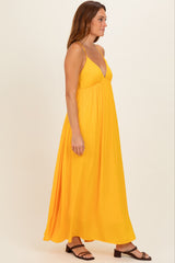 woman wearing a bright yellow spaghetti strap maxi dress standing sideways with a loose, flowing silhouette
