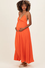 woman wearing an orange maternity maxi dress with a deep V-neck and holding her baby bump