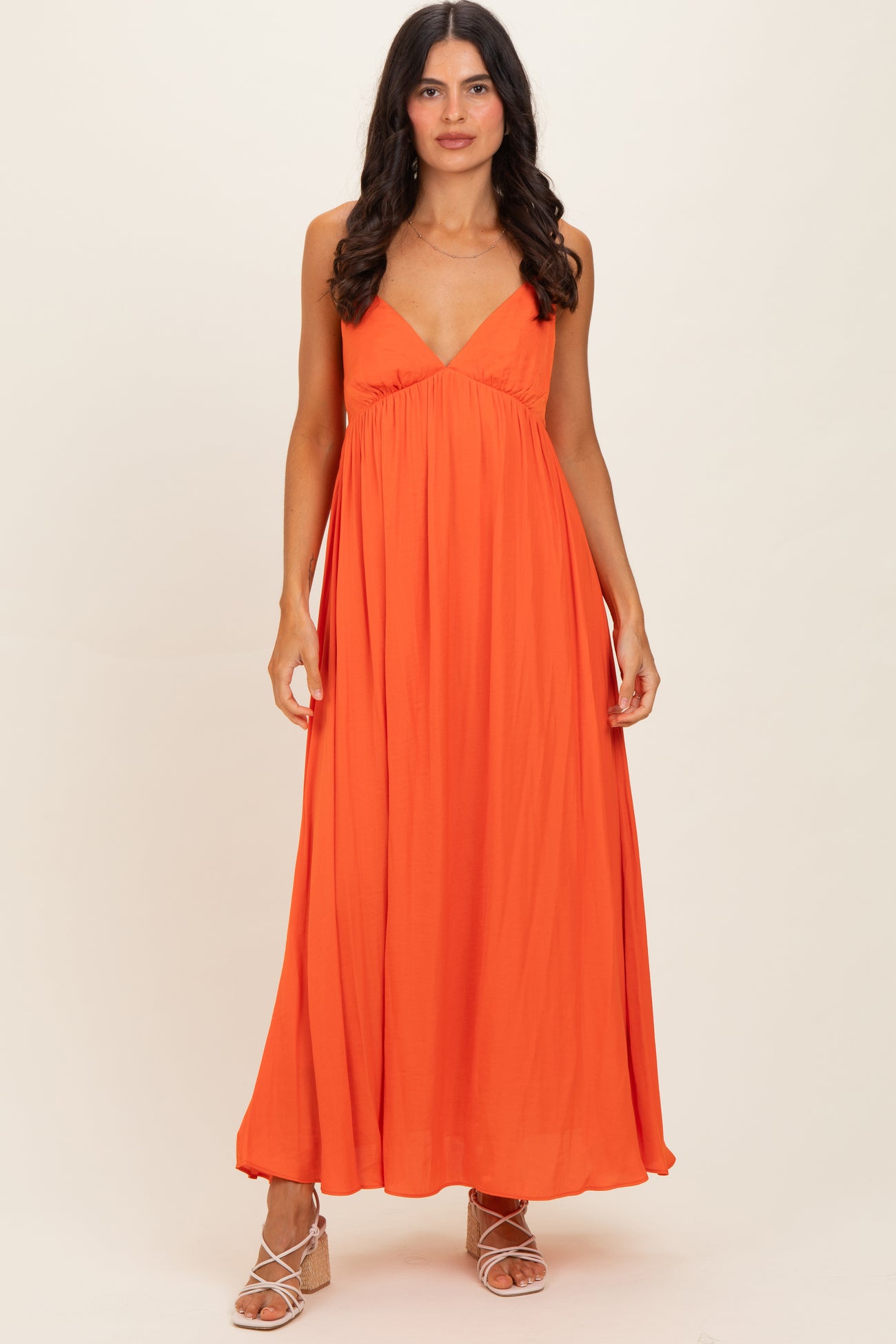 woman wearing a bright orange sleeveless maxi dress with a plunging neckline and a flowing silhouette