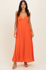 woman wearing a bright orange sleeveless maxi dress with a plunging neckline and a flowing silhouette