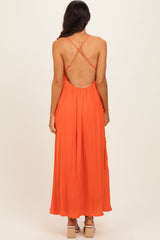 woman wearing a backless orange maxi dress with crisscross straps and flowing silhouette