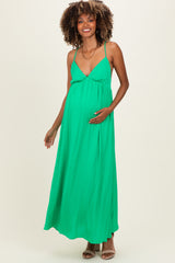 woman wearing a green sleeveless maternity maxi dress and holding her baby bump