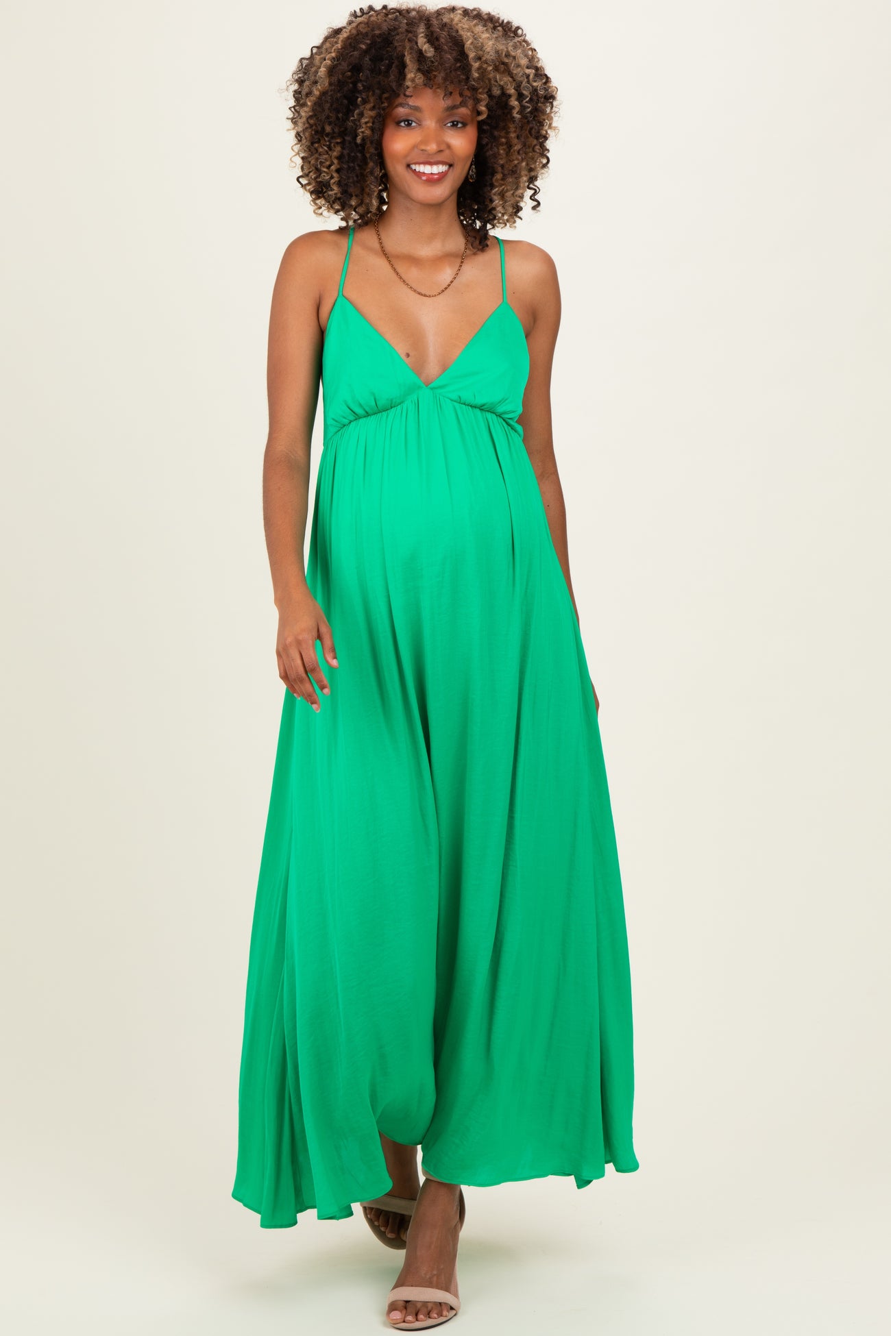 woman wearing a green maternity maxi dress with a deep v-neckline and a flowing silhouette, showcasing her baby bump