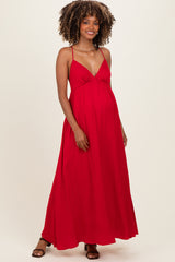 woman wearing a red maxi maternity dress with a gathered bust and spaghetti straps, showcasing her baby bump