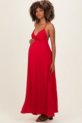 woman wearing a red maxi maternity dress with spaghetti straps and a visible baby bump