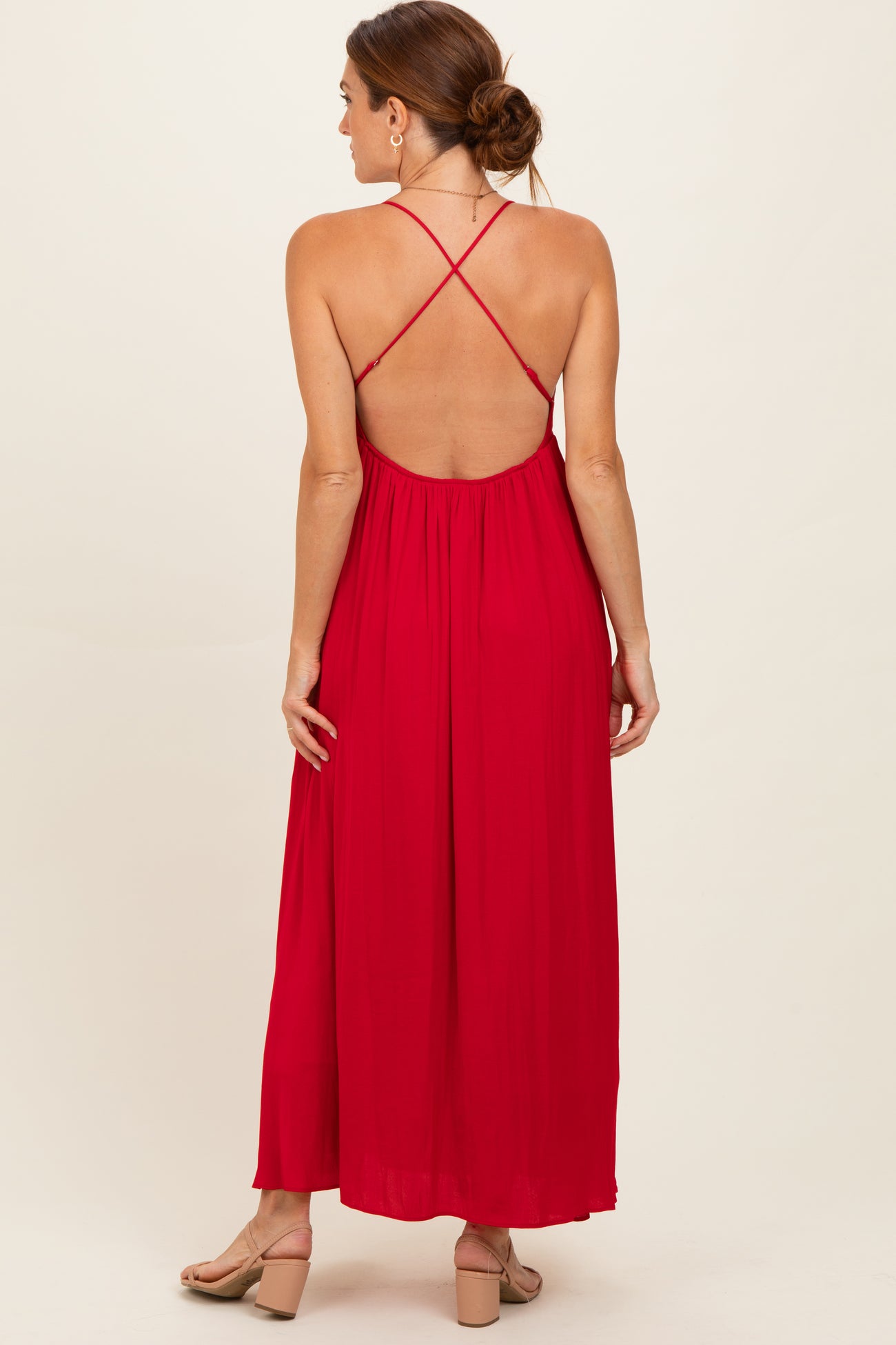 woman wearing a red maxi dress with a back crisscross design and a flowy silhouette