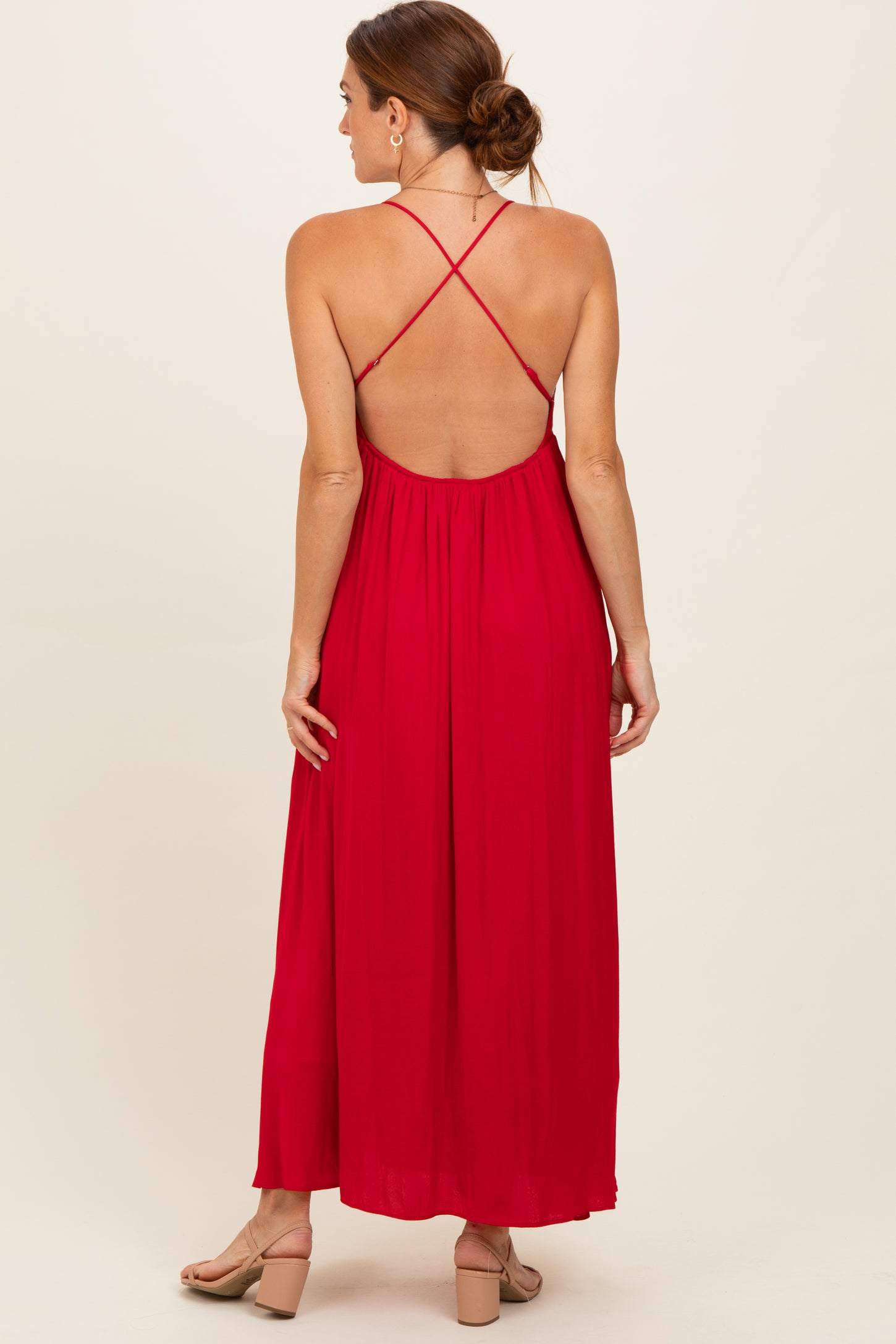 woman wearing a red maxi dress with a back crisscross design and a flowy silhouette