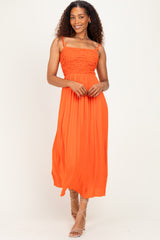 woman wearing an orange spaghetti strap maxi dress with a smocked bodice and flowing skirt