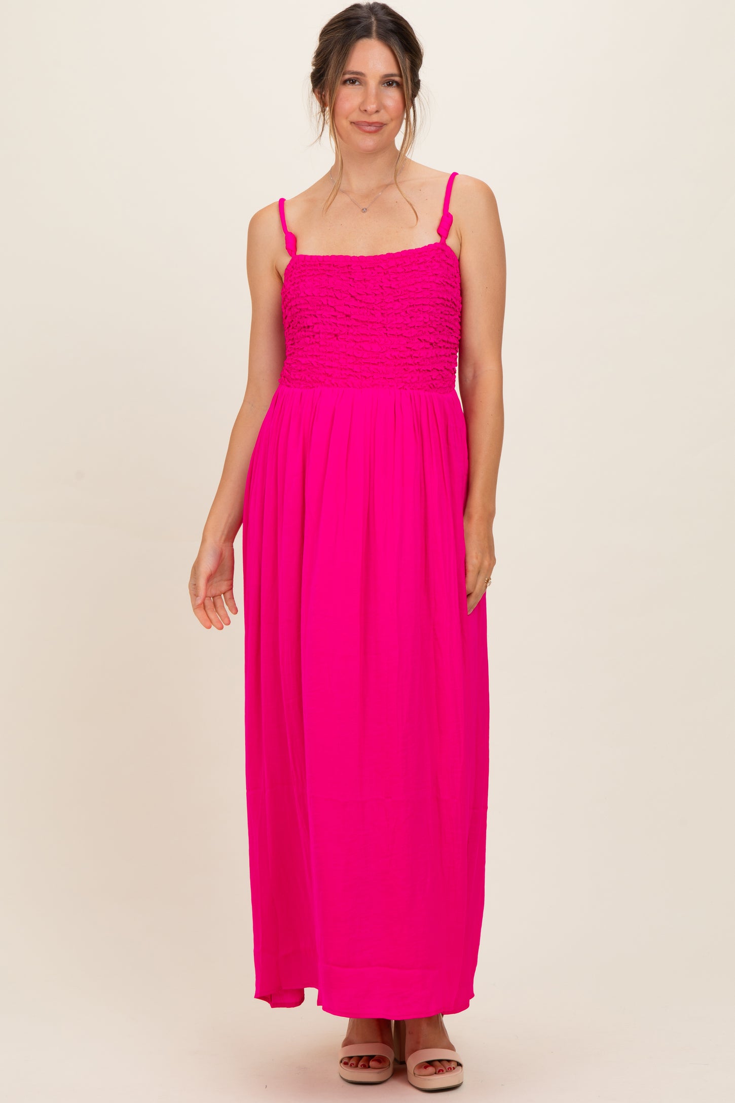 woman wearing a bright pink maternity maxi dress with a smocked bodice and adjustable straps
