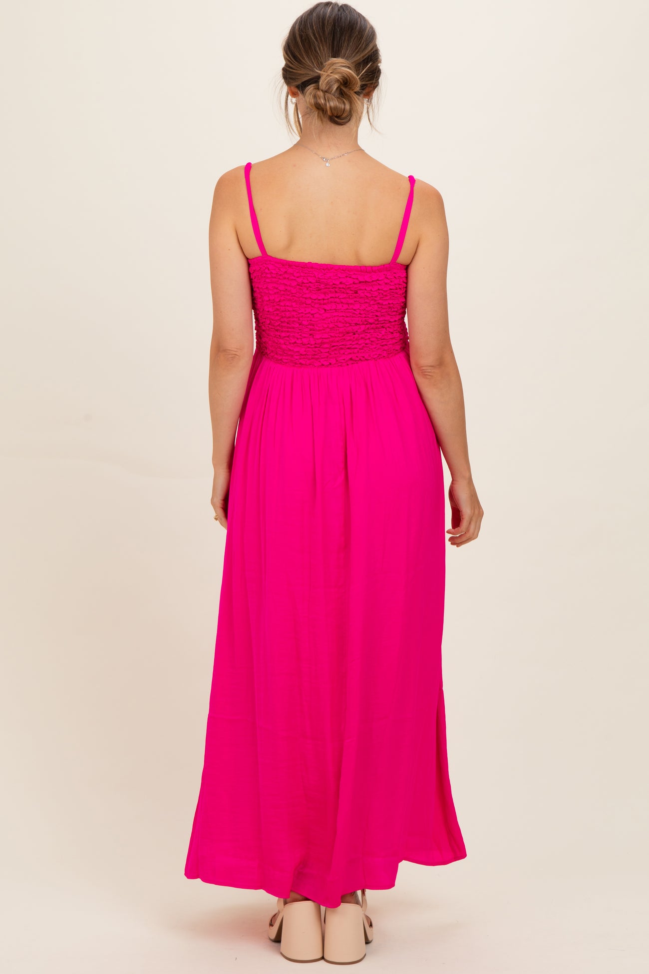 woman wearing a bright pink maternity maxi dress with a smocked bodice and adjustable spaghetti straps