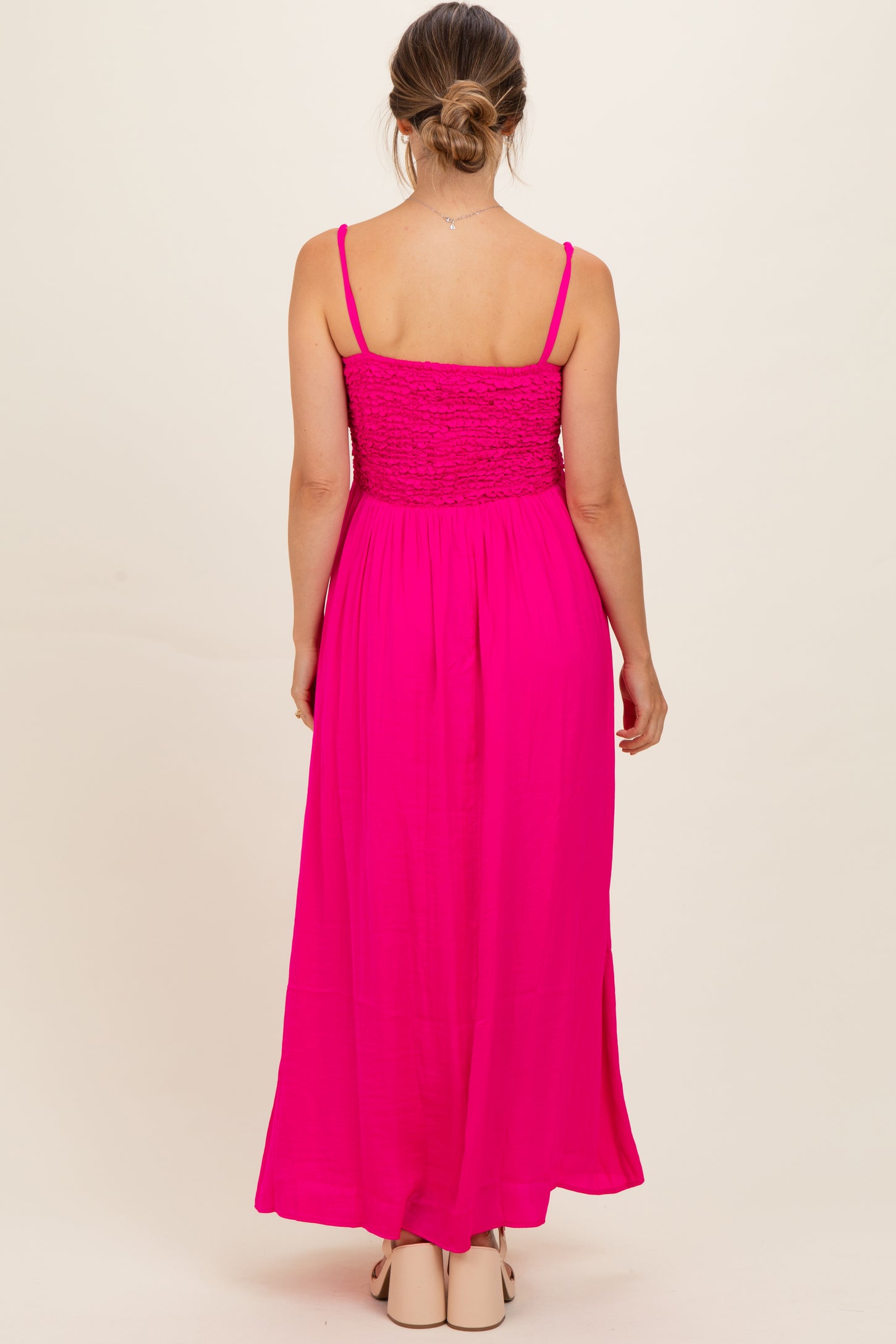 woman wearing a bright pink maternity maxi dress with a smocked bodice and adjustable spaghetti straps