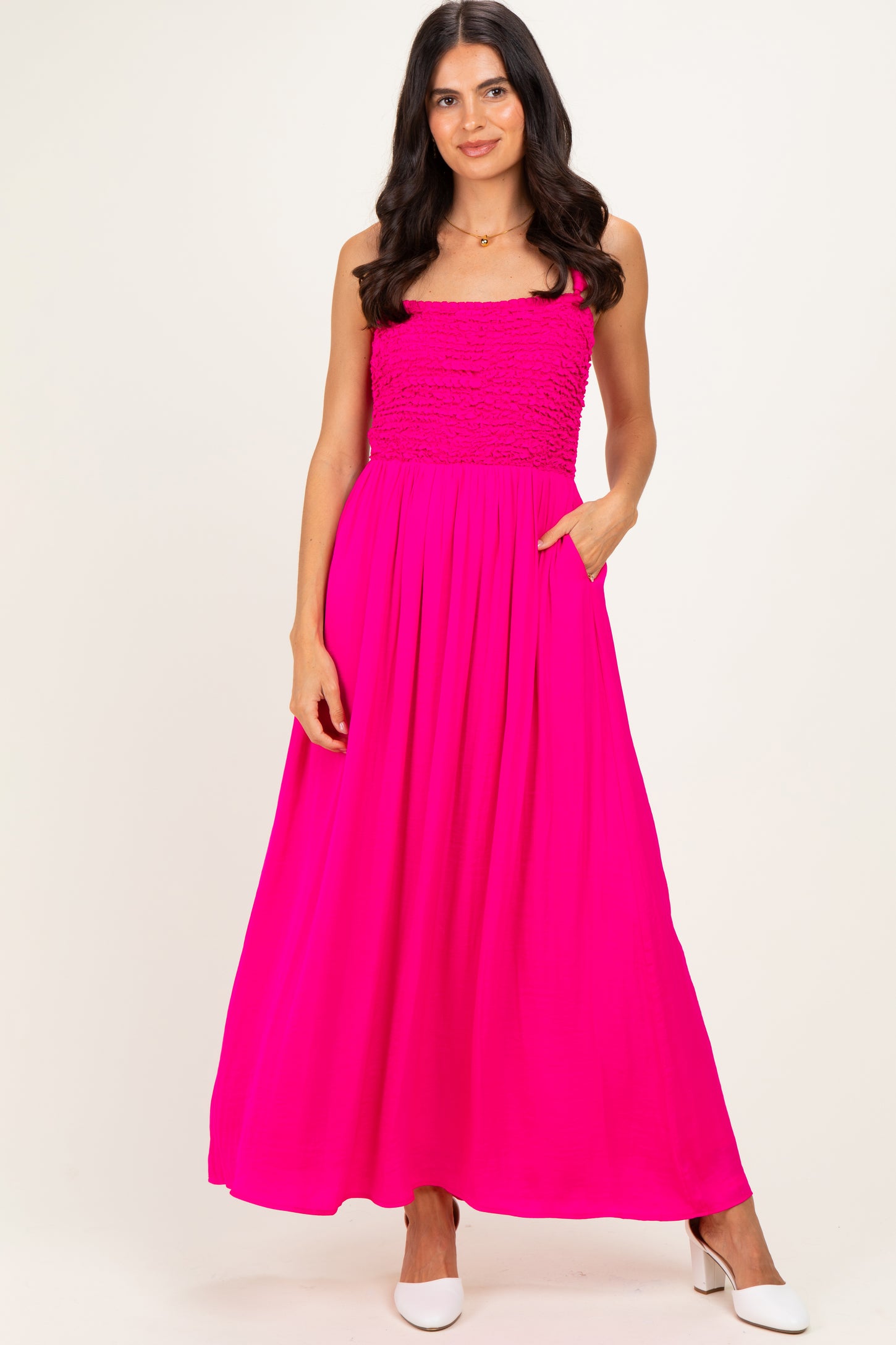 woman wearing a bright pink strapless maxi dress with smocked bodice and pockets