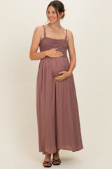 woman wearing a mauve maternity maxi dress with a smocked bodice, cradling her baby bump
