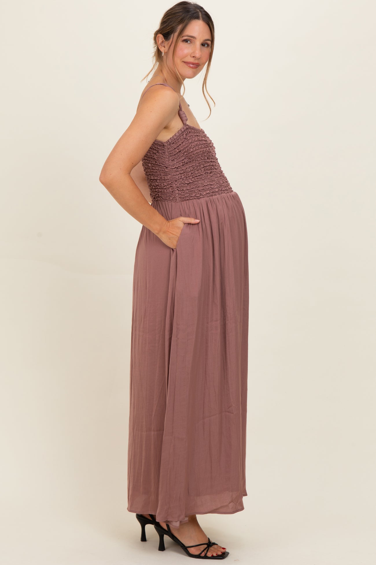 woman wearing a dusty rose maternity maxi dress with smocked bodice and pockets, showing her baby bump