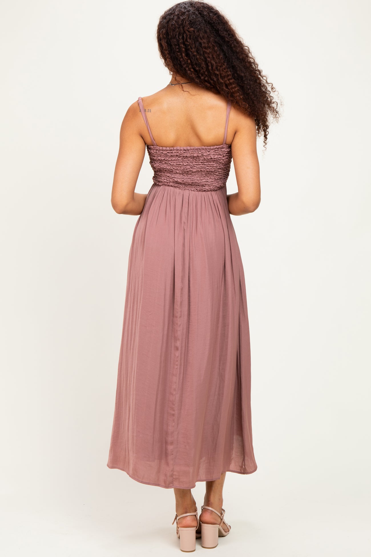 woman wearing a mauve sleeveless maxi dress with a smocked bodice and flowing skirt, shown from the back