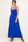 woman wearing a bright blue maxi dress with a smocked bodice and adjustable straps, standing and smiling