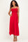 woman wearing a red maxi dress with smocked bodice and thin straps, posing with one hand on her hip