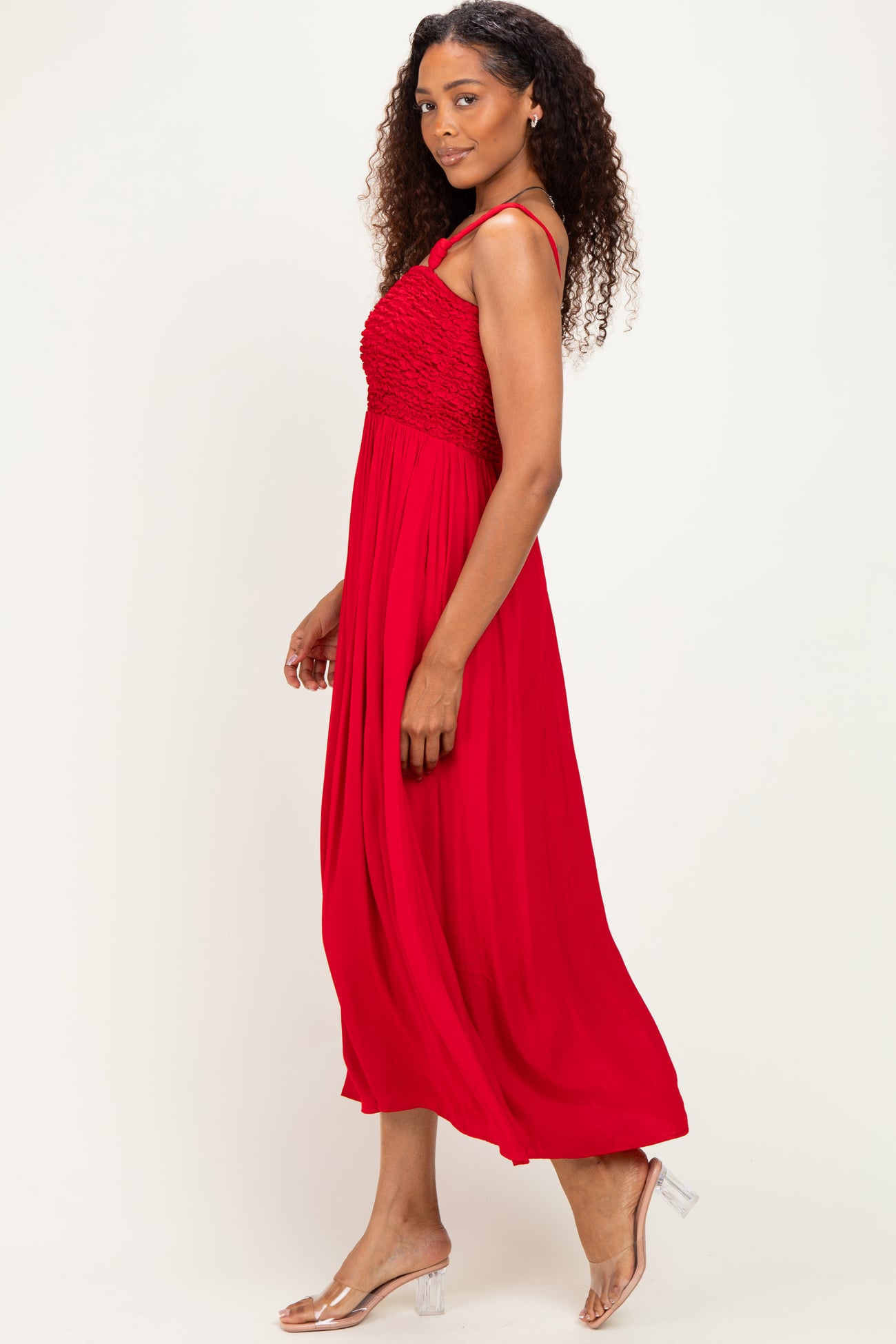 woman wearing a red maxi dress with a smocked bodice and spaghetti straps, standing sideways