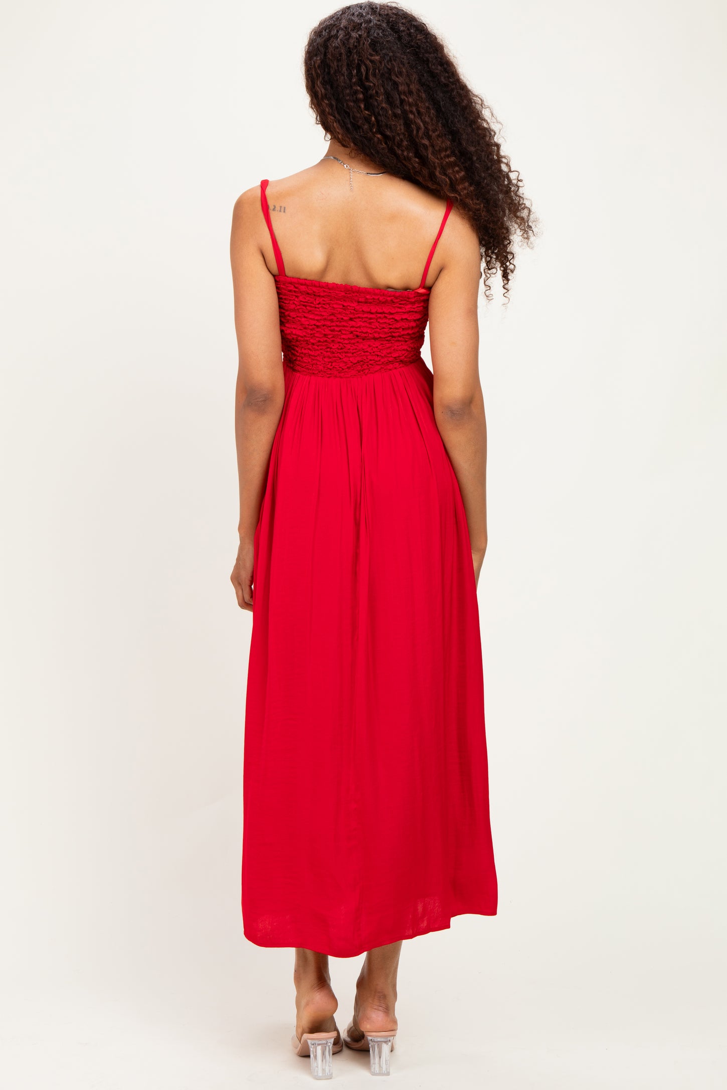 woman wearing a red maxi dress with a smocked back and thin straps, view from the back