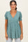 woman wearing a teal floral print short sleeve wrap top with puff sleeves and a gathered waist