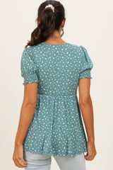 woman wearing a teal peplum top with small white floral print and puff sleeves, shown from the back