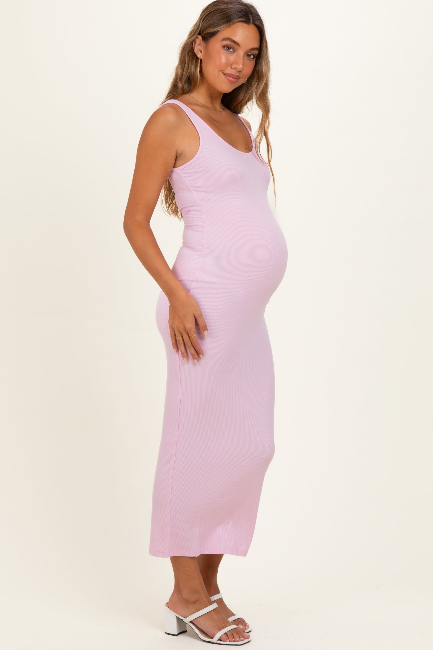 woman wearing a light pink ribbed maternity dress, showcasing her baby bump