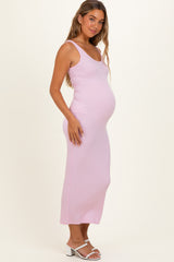 woman wearing a light pink ribbed maternity dress, showcasing her baby bump