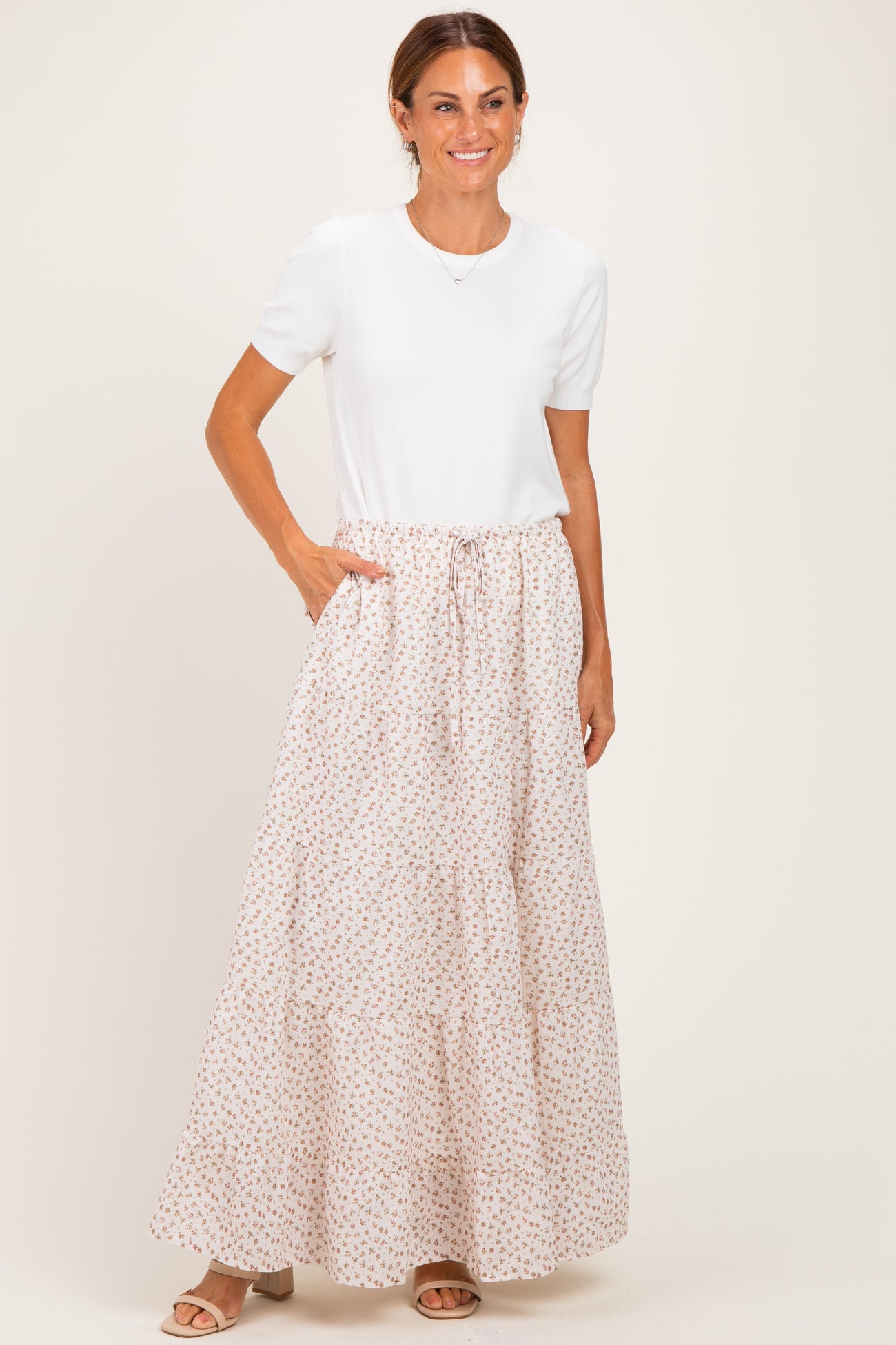 woman wearing a white short sleeve top and a long floral print maxi skirt with pockets